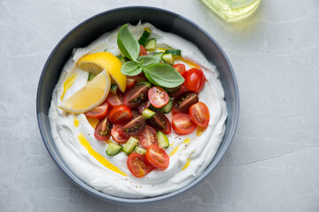 Bowl of tirokafteri or greek feta dip sauce with fresh veggies, horizontal shot on a grey granite background, high angle view
