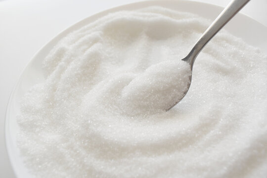 White refined granulated sugar on spoon.