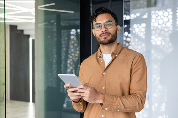 Confident young professional using tablet in modern office environment