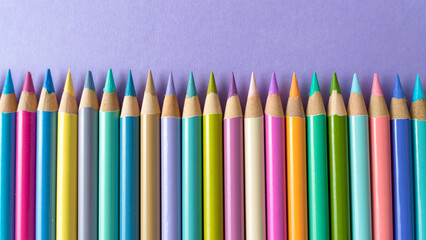 Colorful wooden crayons on a purple paper background