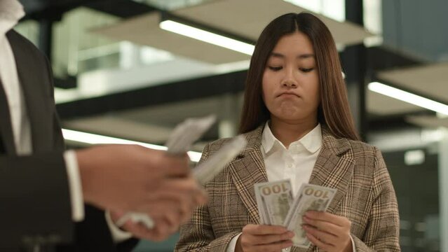 Asian woman Korean female girl businesswoman intern at office counting money cash sad upset looking at happy rich wealthy business man guy male leader businessman financial inequality discrimination