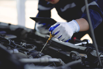 Auto mechanic checking oil in car engine Technician inspects and maintains car engines.