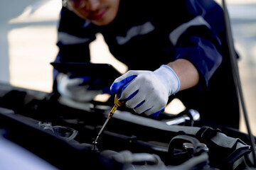 Auto mechanic checking oil in car engine Technician inspects and maintains car engines.