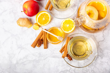 Fragrant hot tea with cinnamon stick and anise on a textured wooden background. A cup of hot tea with honey, lemon, mint and apples. Spicy tea with spices. Immunity tea. Health concept.Copy space.