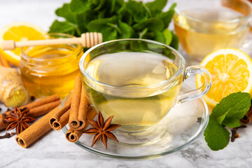 Fragrant hot tea with cinnamon stick and anise on a textured wooden background. A cup of hot tea with honey, lemon, mint and apples. Spicy tea with spices. Immunity tea. Health concept.Copy space.