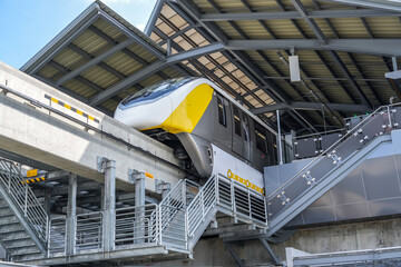 Monorail train arrives at a passenger intermediate station on a minibus station built on bridge...