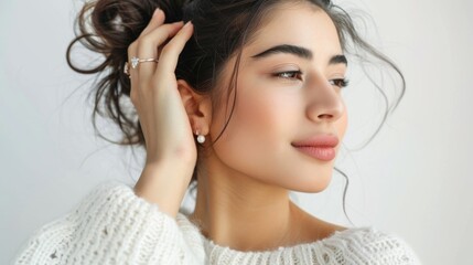 Fototapeta premium an isolated woman trying on earrings, feeling elegant, on a clean white background.