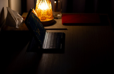  An aesthetic picture of laptop and pen with small amount of light from the lamp. Working at night concept.But Empty person.