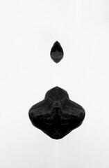 Abstract symmetry of black figures on a plain white background, simulating black droplets