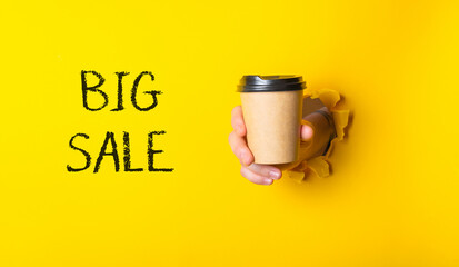 A person is holding a coffee cup with the words Big Sale written on it