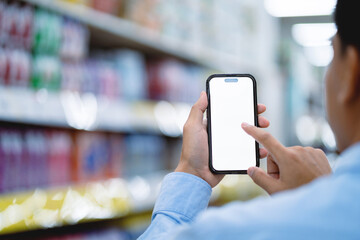 A man is holding a cell phone in a store and is looking at the screen