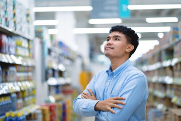 Asian young man choosing in supermarket Male customers standing in the grocery store.