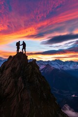 Two people shaking hands at the top of a mountain at sunrise