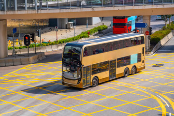 Double-decker city shuttle bus at an intersection with markings rides down the street, aerial view