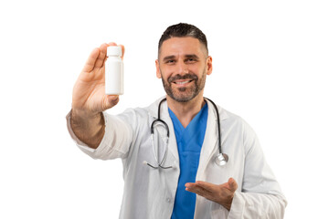 A friendly doctor with a beard and stethoscope, wearing a white lab coat, smiles while holding a small medicine bottle in a studio setting.