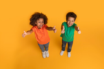 Two African American children, a boy and a girl, are enthusiastically giving thumbs up gestures...