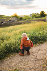 A little baby running on the grass at sunset and enjoying life. A game of catch-up with a toddler. Fun and activities for children on the street. Happy childhood.