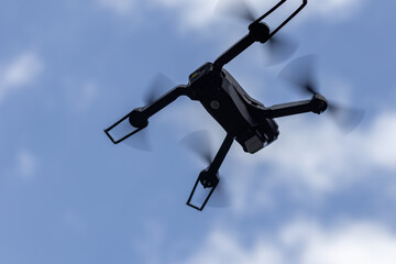 Drone flies in the air at a low altitude against a blue sky. Drone makes photos. Modern new technology. Ready background with place for your text.

