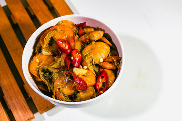 Shrimp dishes with butter sauce in a white porcelain bowl and on a wooden coaster