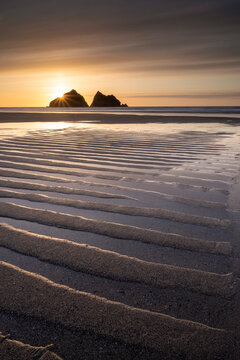 Holywell Bay at low tide, ripples and reflections at sunset, looking towards Carter's Rocks. Cornwall, UK. March.  
