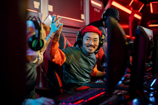 Happy Asian gamer celebrating with teammates at a competitive gaming event