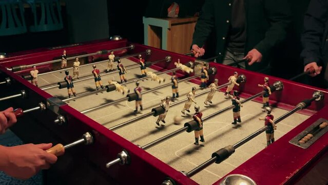 People playing in table football or kicker with miniature players. Table football game. Employees playing table soccer indoor-game in the office during break time.