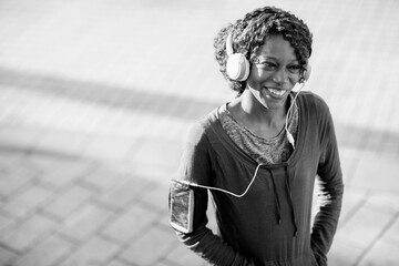 Smiling young woman jogging outside with headphones