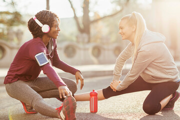 Two women stretching and talking before a workout outdoors