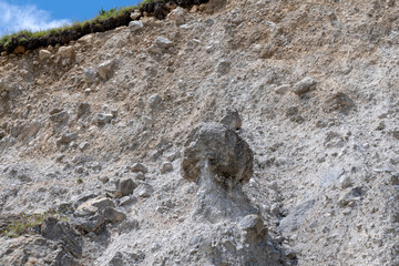 A huge boulder on top of a sandy mountain. Soil erosion and rockfall in the mountains