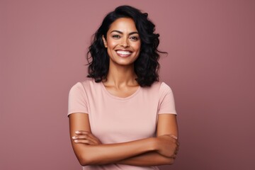 Fototapeta premium Portrait of a happy indian woman in her 30s with arms crossed in blank studio backdrop