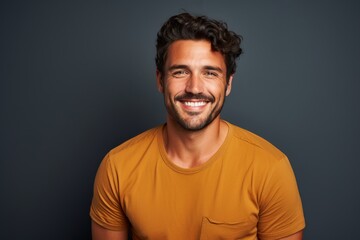 Fototapeta premium Portrait of a cheerful man in his 30s smiling at the camera while standing against blank studio backdrop