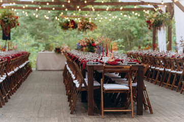 wedding holiday banquet in the open air. covered, served tables in the yard, garden in nature. wooden tent covered with fabric, wedding banquet