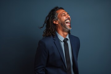 Fototapeta premium Portrait of a tender indian man in his 40s laughing while standing against blank studio backdrop
