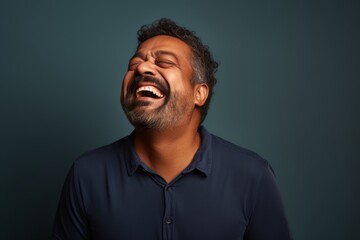 Fototapeta premium Portrait of a tender indian man in his 40s laughing isolated in blank studio backdrop