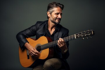 Obraz premium Portrait of a satisfied man in his 40s playing the guitar in blank studio backdrop
