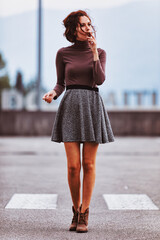 Obraz premium Brown top, grey skirt, thoughtful expression, blurred background