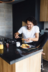 latin man preparing and eating a healthy breakfast with fruit orange juice in kitchen at home in Mexico Latin America, hispanic people	