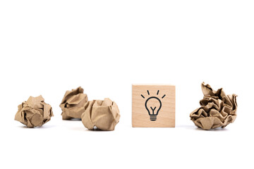 Crushed paper balls and wooden cube with light bulb symbol on it, concept of original idea,...