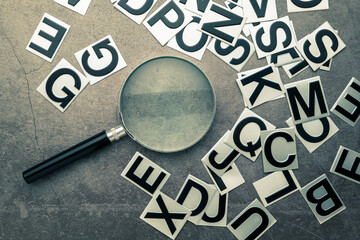 Magnifying glass and English alphabet stickers scattered on the table, glossary, words selection to...