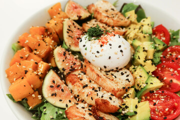 close up of salad with boiled egg, cherry tomato, avocado, fig, pumpkin and lettuce with black...