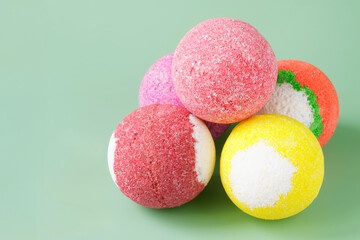 Five colorful bath bombs on a light green background. Copy space. Photo