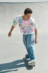 A young man skillfully rides a skateboard on a ramp at an outdoor skate park on a sunny summer day.