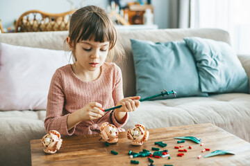 A sweet little girl is engrossed in her creative activity, arranging small colorful construction...