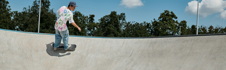 A young skater boy rides a skateboard up the ramp in an outdoor skate park on a sunny summer day.