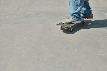 A young skater boy effortlessly rides a skateboard on a smooth cement surface in a vibrant outdoor...