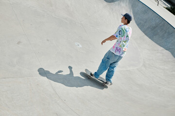 A young skater boy performing a daring skateboard descent down the ramp at an outdoor skate park on a sunny summer day. - Powered by Adobe