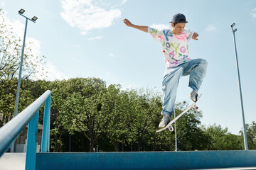 A young skater boy fearlessly rides his skateboard down the side of a vibrant blue rail in a summer...