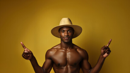 Shirtless confident male model in straw hat gesturing upwards against a solid yellow backdrop