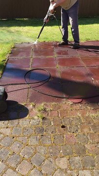 Man cleaning stone garden paths with high pressure power washer. Rubber-coated platform washing. Vertical video. Taken from hand. High quality 4k footage