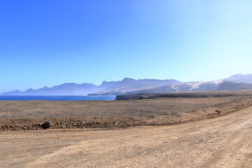 Gravel, dusty road with high volcanic mountains in the background. Jandia, Morro Jable, Fuerteventura, Canary Islands, Spain